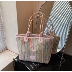 Detail of multi-color striped woven tote with pink leather handle and brand patch