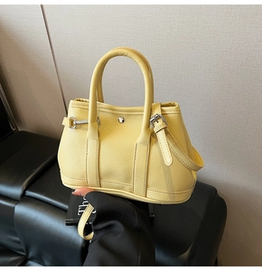 Detailansicht der gelben Handtasche aus Leder mit Narbenstruktur und silberner Schnalle