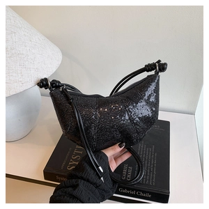 Detailed macro view of black sequined croissant bag with stylish knotted strap detail
