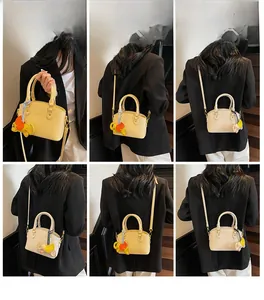 Detail view of yellow shell-shaped handbag with cute elephant charm and long strap