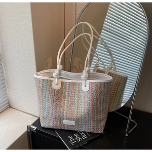Detail of colorful striped woven tote bag with white leather handle and knotted accents