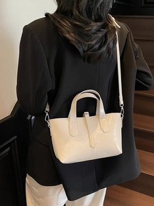 Fashionable cream white glossy leather tote bag shown on model in a stylish indoor setting