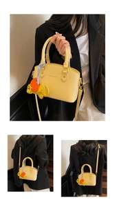 Detail view of yellow crossbody bucket bag with elephant charm and fashion logo
