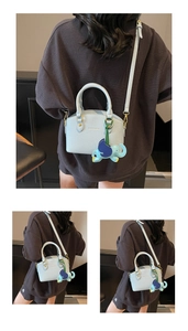Detail of light blue bucket bag with pebble leather texture and elephant charm