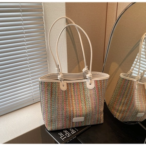 Detail of colorful woven tote bag featuring striped texture and white leather handle
