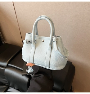 Details einer hellblauen Beuteltasche mit Lychee-Ledertextur und runder Metallschnalle