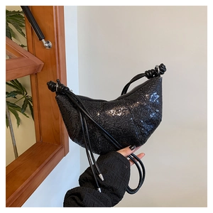 Detail of black sequined crescent bag showing textured glitter and leather knot strap
