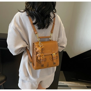 Details des braunen Vintage-Lederrucksacks mit Bärenanhänger und akademischem Aufdruck
