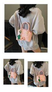 Detail of pink pebbled leather bucket bag with green elephant charm and logo text