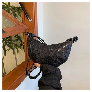Close-up of black sequined croissant bag showing shimmering texture and knot detail