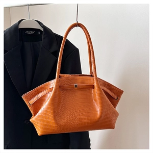Detail of orange crocodile pattern leather bag with sleek handle and wing structure