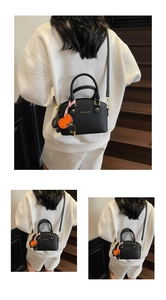 Detail of black lychee grain leather bucket bag with gold lettering and elephant charm