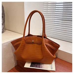 Detail of crocodile embossed texture on a brown orange wing-shaped tote bag