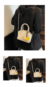Detailed view of beige bucket bag with elephant charm and gold hardware on stairs