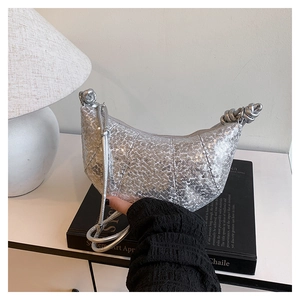 Close-up of silver sequin hobo bag with pleated texture and metallic knotted handle