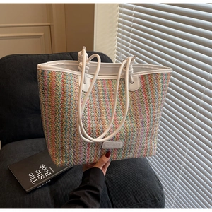 Detail of colorful striped woven tote bag featuring white leather trim and brand plate