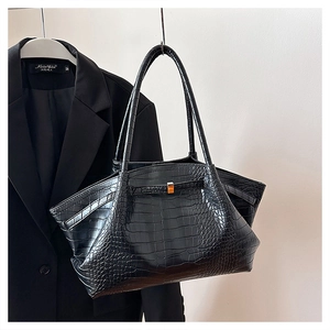 Detail shot of black crocodile embossed tote bag hanging on a professional blazer