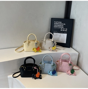 Five colored minimalist bucket bags on display with leather elephant charm accessories