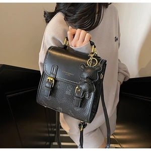 Detailansicht der schwarzen Lederhandtasche mit goldenem KEDDYBEAR-Logo und Bärenanhänger