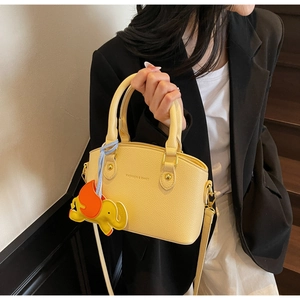 Detailed shot of yellow textured leather crossbody bag with cute elephant charm