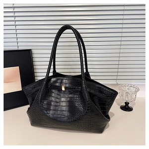 Detail of black crocodile texture bag featuring elegant gold clasp and wing shape design