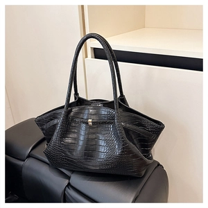 Detail view of black crocodile-embossed leather tote bag with elegant metallic lock closure