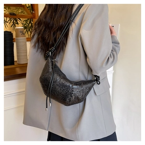 Detail of a black sequin crescent bag with an elegant knotted strap design on the shoulder