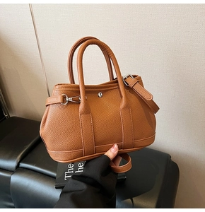 Detail der braunen Bucket Bag mit Litschi-Muster, silbernem Verschluss und Riemen