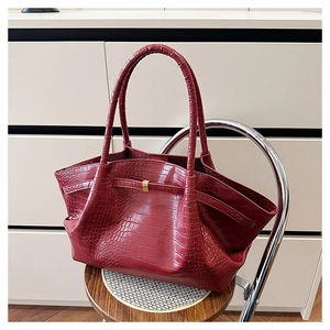 Macro shot of burgundy faux crocodile texture and gold buckle on a chic handbag