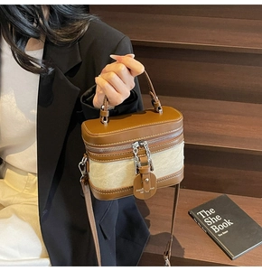 Detail shot of a vintage brown leather and beige canvas cylinder box bag with top handle