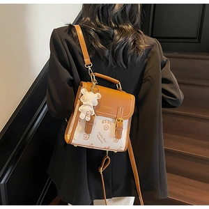 Klassischer Rucksack aus Leder in Braun und Beige an einem Modell mit Bärenanhänger