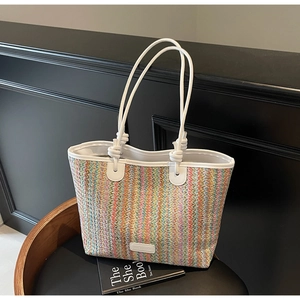 Detail of colorful striped woven tote bag with white leather straps on a black chair
