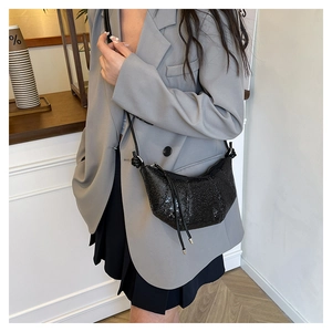 Detail of black sequined crescent bag showing shimmering texture and silver metal aglets