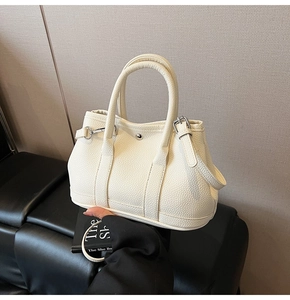 Detailansicht der cremefarbenen Lederbeuteltasche mit Silberbeschlägen und Trageriemen