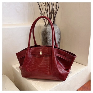 Close-up of deep burgundy crocodile-embossed leather tote with elegant gold metal buckle