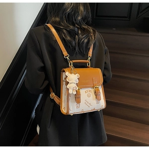 Detail eines braunen Leder-Mini-Rucksacks mit Bärendruck und Plüschtier-Anhänger