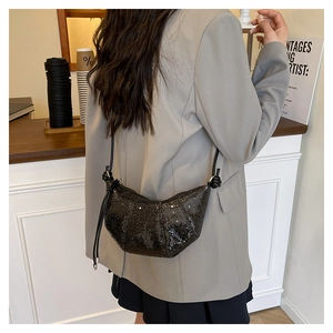 Detailed view of black sequined crescent bag with knotted shoulder strap on model
