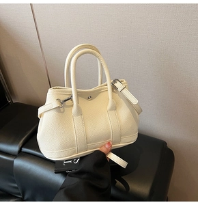 Detailansicht der beigen Handtasche aus Leder mit Litschistruktur und silbernen Schnallen