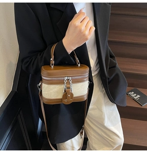 Detailed view of canvas and leather crossbody box bag styled on a female model