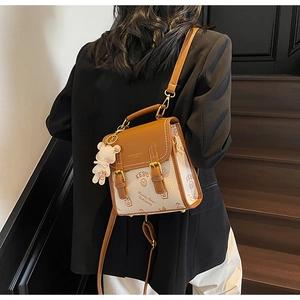 Detail eines bedruckten Mini-Rucksacks in Braun und Beige mit süßem Bären-Plüschanhänger
