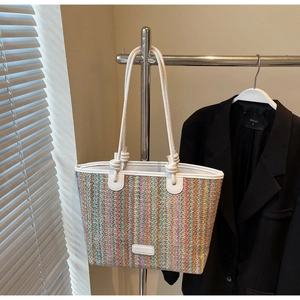 Detail of colorful woven tote bag featuring white leather straps and unique knot accents