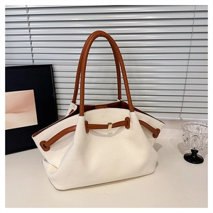 Detail of off-white canvas tote with brown leather straps and gold buckle accents