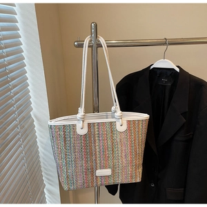 Detail of colorful striped woven tote bag with white rope handles and brand tag