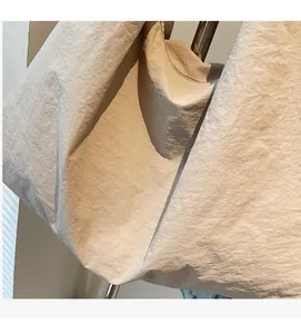 Close-up of lightweight off-white nylon tote bag showing soft wrinkled fabric texture