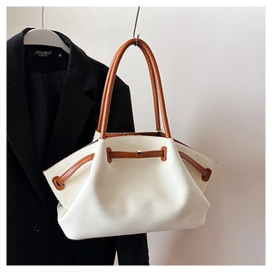 Detail of stone pattern wing bag with beige canvas and brown leather straps on a hanger
