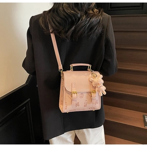 Rosa Rucksack mit Bären-Prägung auf Vintage-Holztreppe an Person im Detail gezeigt