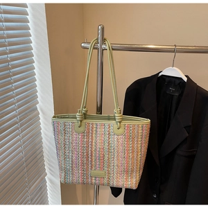 Close-up of colorful striped woven tote bag with light green leather handles and brand tag