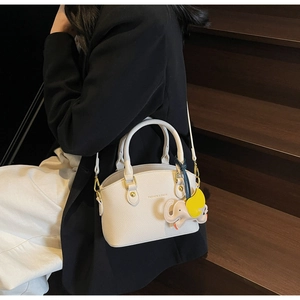 Detail of white litchi pattern shell bag featuring a cute elephant charm accessory