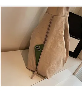 Detail view of the hidden side zipper pocket on a beige nylon tote bag with a smartphone