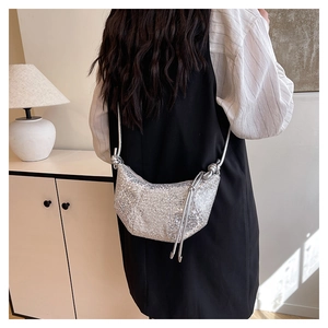 Detail of silver sequined half-moon crossbody bag with rope strap on a model outfit
